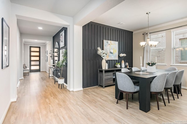 dining area with baseboards, light wood-type flooring, a wealth of natural light, and a chandelier