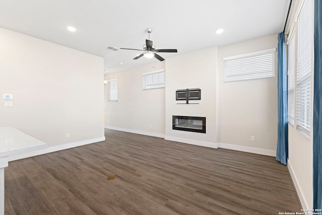 unfurnished living room with visible vents, baseboards, ceiling fan, and dark wood finished floors