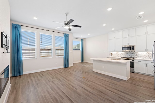 kitchen with visible vents, decorative backsplash, stainless steel appliances, a ceiling fan, and a sink