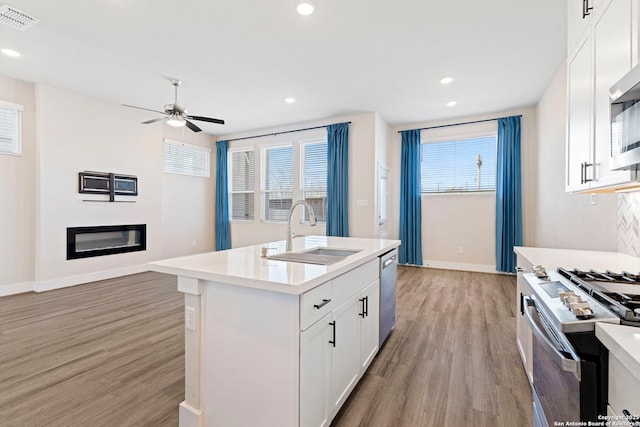 kitchen featuring visible vents, light wood-style floors, stainless steel appliances, a ceiling fan, and a sink