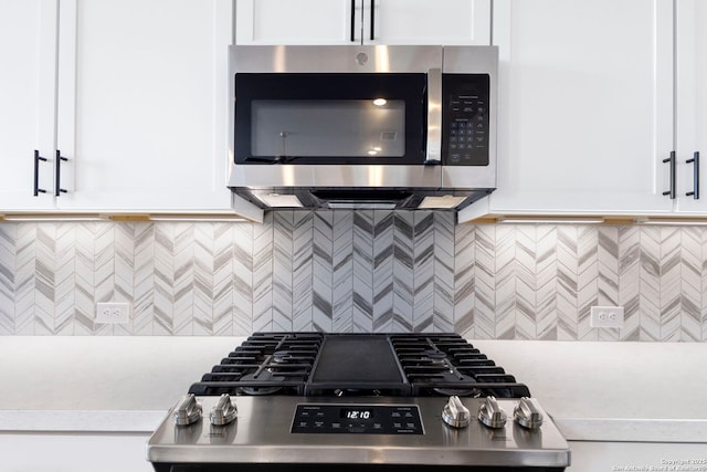 kitchen with tasteful backsplash, white cabinets, stainless steel appliances, and light countertops