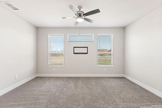 carpeted spare room with a textured ceiling, baseboards, visible vents, and ceiling fan