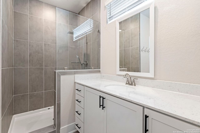 bathroom with tiled shower and vanity