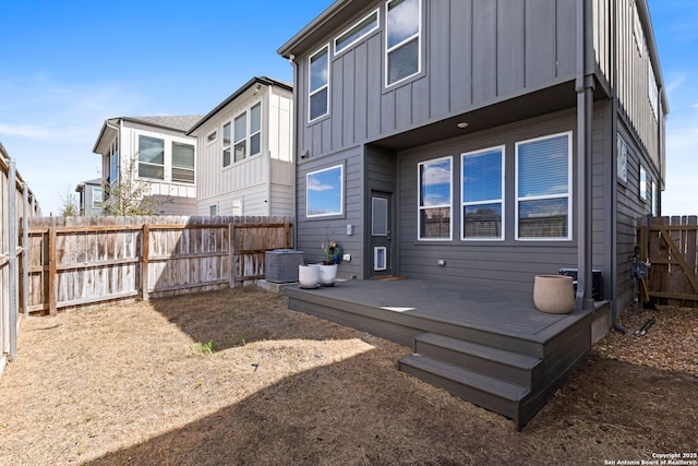 back of house featuring a deck, cooling unit, board and batten siding, and a fenced backyard