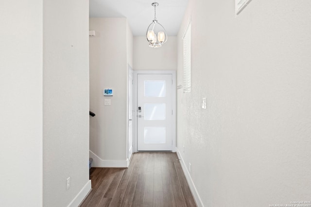 doorway featuring baseboards, an inviting chandelier, and wood finished floors