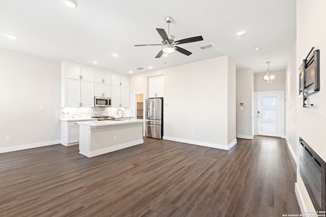 kitchen featuring backsplash, dark wood finished floors, open floor plan, light countertops, and appliances with stainless steel finishes