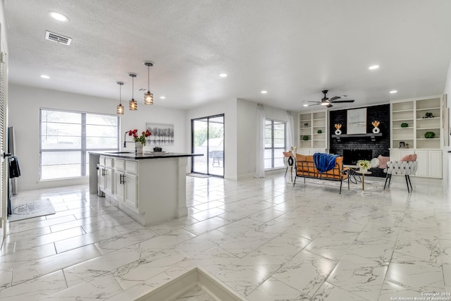 kitchen with built in features, visible vents, a fireplace, marble finish floor, and open floor plan