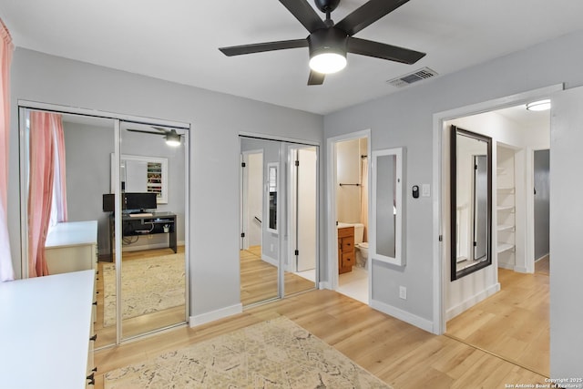 bedroom with visible vents, multiple closets, baseboards, and wood finished floors