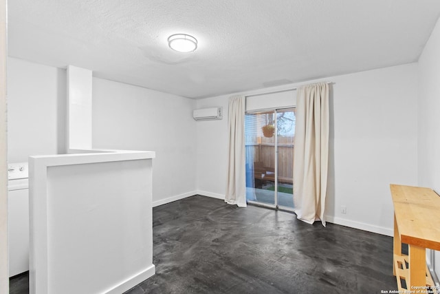 interior space featuring baseboards, a textured ceiling, washer / clothes dryer, and a wall unit AC