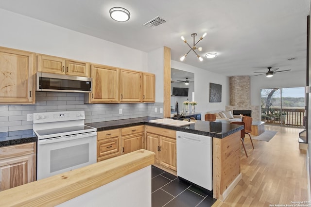 kitchen featuring white appliances, a ceiling fan, light brown cabinetry, and a sink