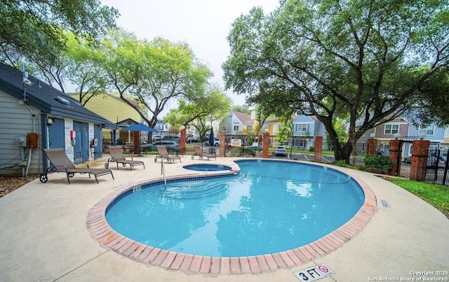 view of swimming pool featuring a patio area, a residential view, fence, and a hot tub