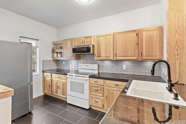 kitchen featuring light brown cabinetry, decorative backsplash, a sink, appliances with stainless steel finishes, and dark tile patterned floors