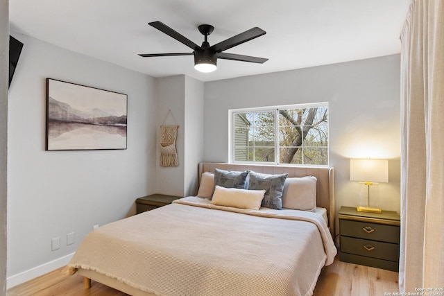 bedroom with a ceiling fan, light wood-style floors, and baseboards