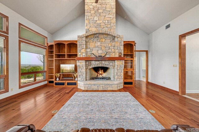 unfurnished living room with hardwood / wood-style flooring, a fireplace, visible vents, and high vaulted ceiling