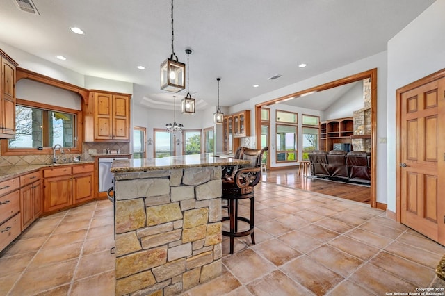 kitchen with light stone countertops, dishwasher, tasteful backsplash, open floor plan, and a center island