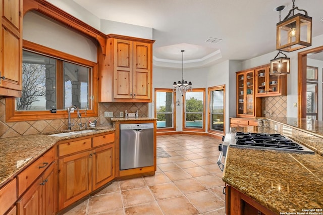 kitchen with a sink, decorative backsplash, stainless steel dishwasher, a raised ceiling, and a chandelier