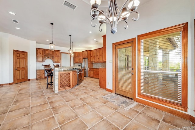 kitchen featuring a breakfast bar area, brown cabinetry, visible vents, baseboards, and appliances with stainless steel finishes