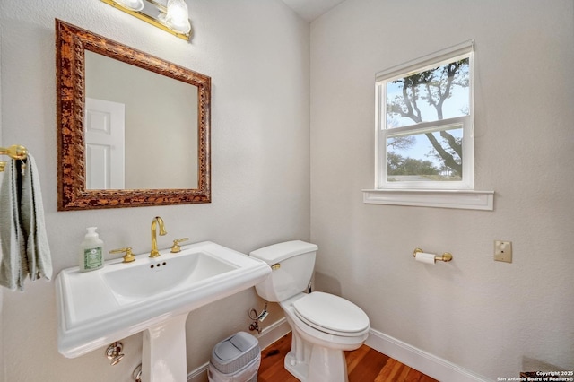 bathroom featuring a sink, toilet, baseboards, and wood finished floors