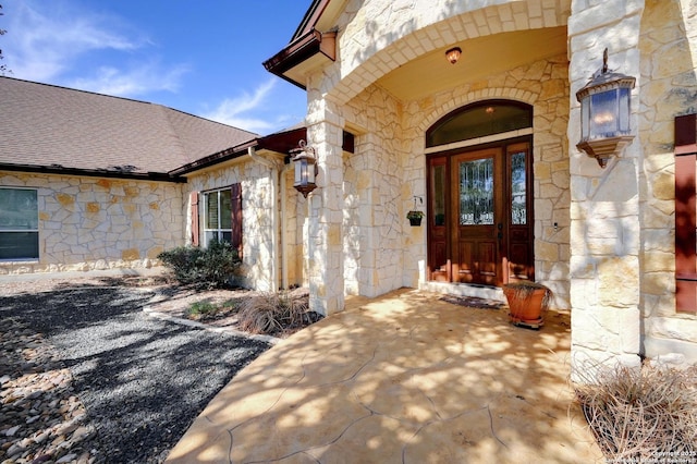 property entrance with stone siding and roof with shingles