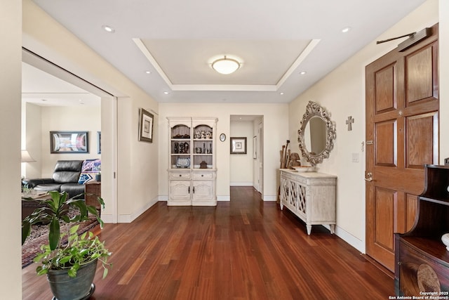 corridor with built in shelves, baseboards, recessed lighting, wood finished floors, and a raised ceiling