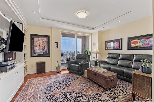 living area with recessed lighting, baseboards, a raised ceiling, and wood finished floors