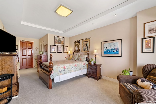 bedroom featuring light colored carpet, baseboards, and a tray ceiling