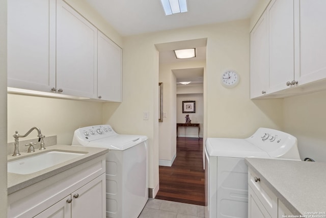 laundry area featuring light tile patterned floors, baseboards, washing machine and clothes dryer, cabinet space, and a sink