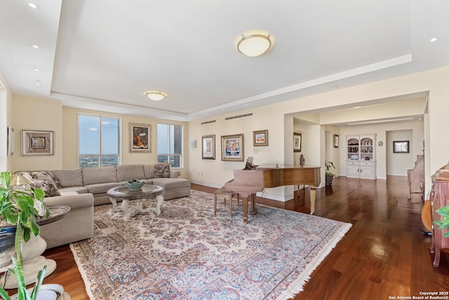 living room featuring a raised ceiling, recessed lighting, wood finished floors, and baseboards