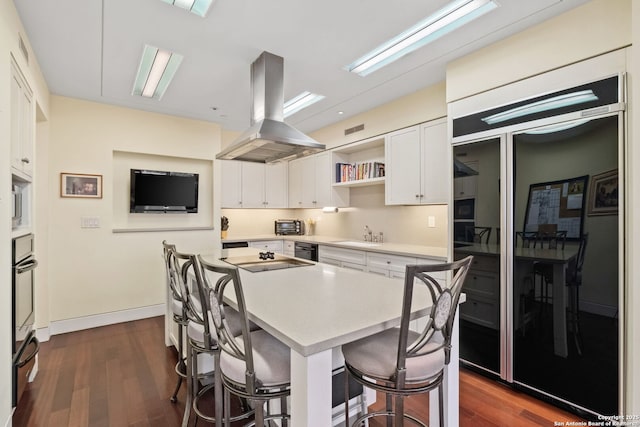 kitchen featuring a kitchen breakfast bar, white cabinetry, open shelves, and island range hood