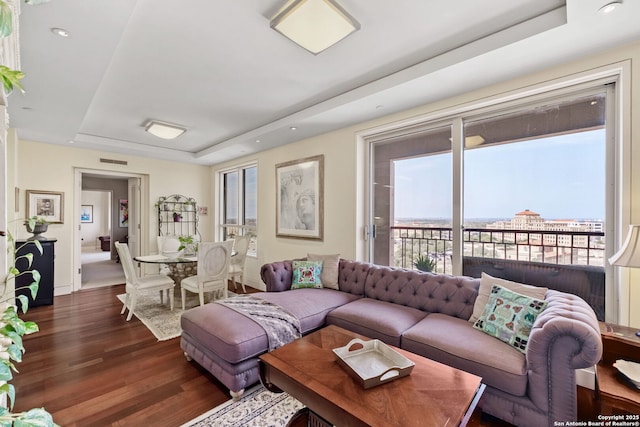 living room with visible vents, recessed lighting, a raised ceiling, and dark wood-style flooring