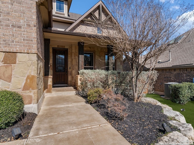 doorway to property featuring cooling unit and stone siding