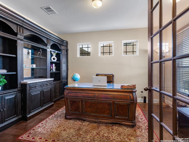 office area featuring dark wood-type flooring, baseboards, visible vents, and a textured ceiling