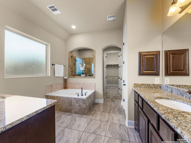 bathroom with visible vents, a walk in closet, a garden tub, a tile shower, and vanity