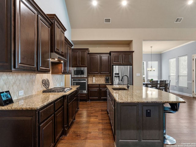 kitchen featuring visible vents, a breakfast bar area, stainless steel appliances, and a sink