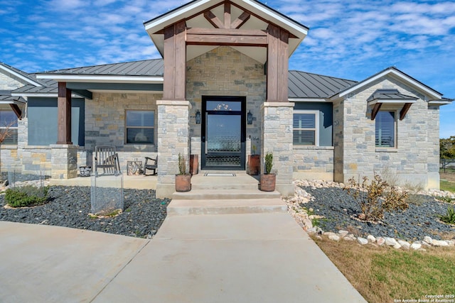 entrance to property with metal roof, stone siding, and a standing seam roof