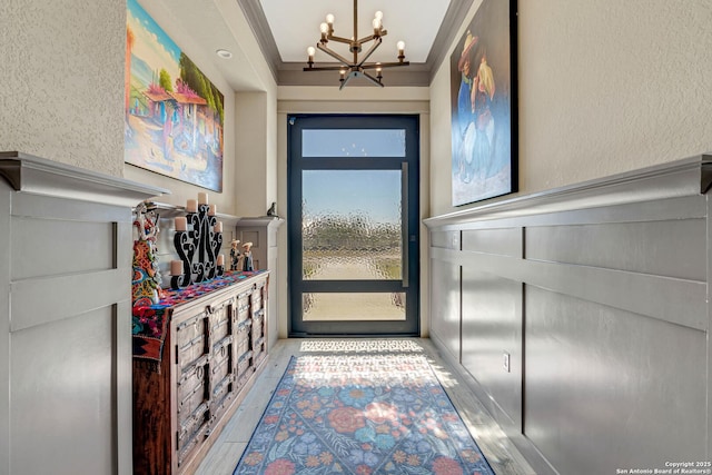 doorway featuring crown molding, an inviting chandelier, and wood finished floors