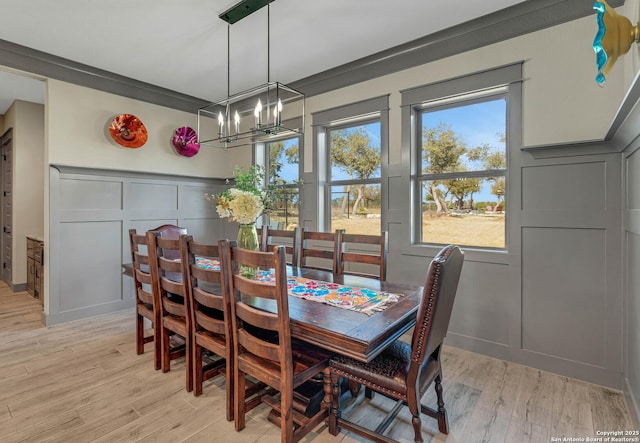 dining room with a decorative wall, an inviting chandelier, and light wood-style floors