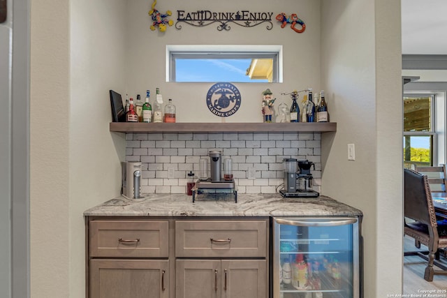 bar with wine cooler, decorative backsplash, a healthy amount of sunlight, and indoor bar