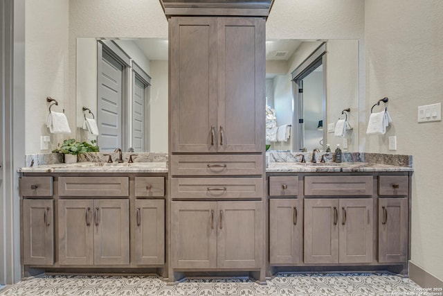 full bath with vanity and a textured wall