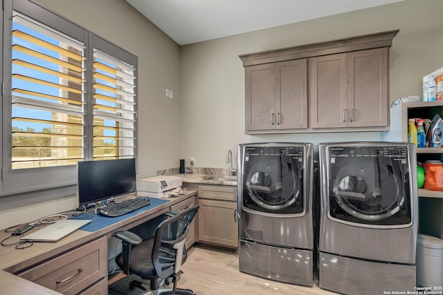 clothes washing area featuring cabinet space, washer and dryer, light wood-type flooring, and a sink