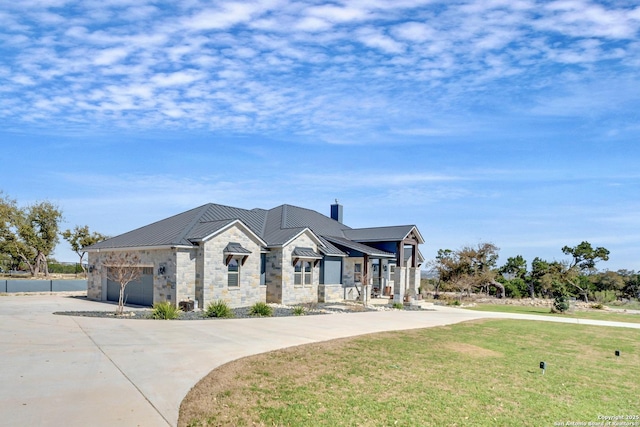 view of front of home with stone siding, concrete driveway, metal roof, and a standing seam roof