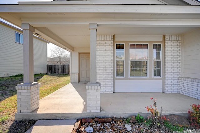 doorway to property with brick siding and a porch