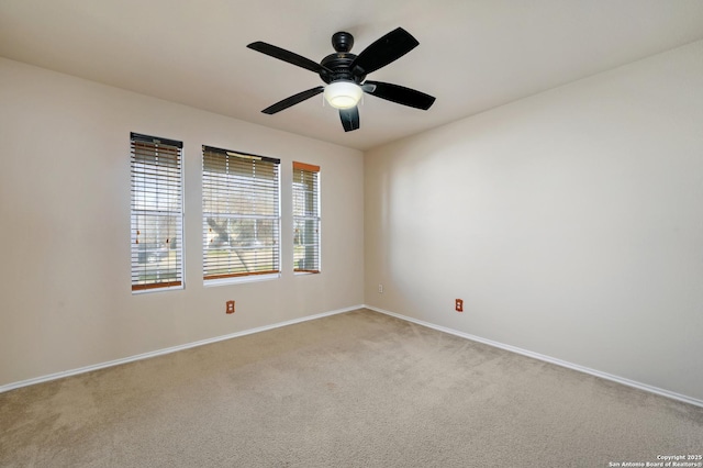 carpeted spare room featuring baseboards and a ceiling fan