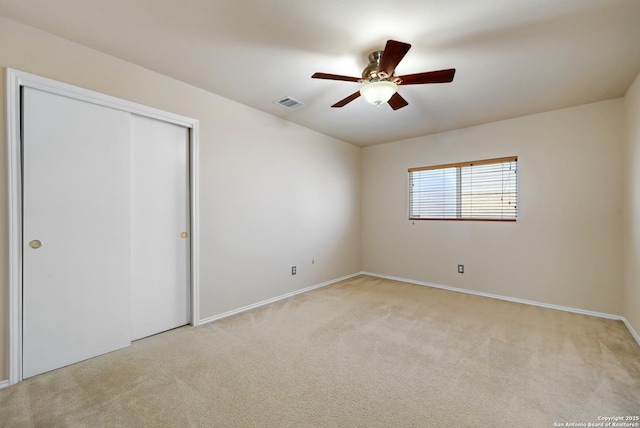 empty room with visible vents, light colored carpet, and ceiling fan