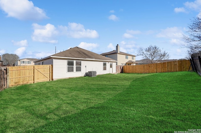 rear view of property with a yard, central air condition unit, and a fenced backyard