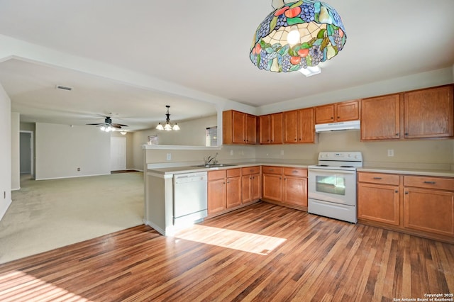 kitchen featuring under cabinet range hood, a sink, white appliances, light wood finished floors, and light countertops