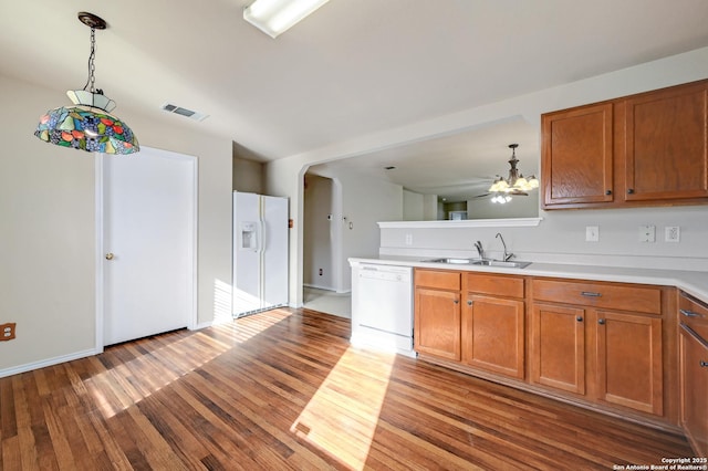 kitchen featuring light countertops, wood finished floors, brown cabinetry, white dishwasher, and a sink