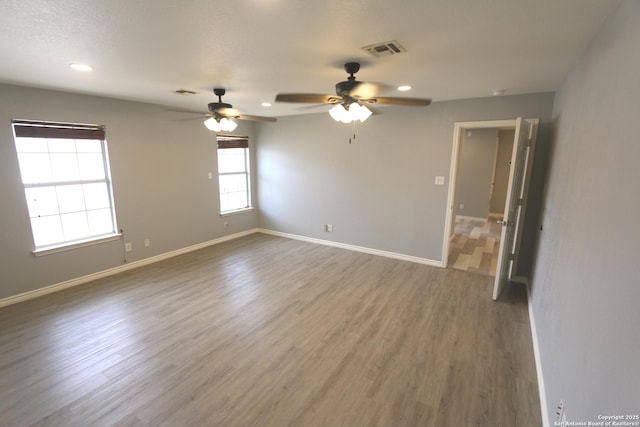 unfurnished room featuring ceiling fan, visible vents, baseboards, and wood finished floors