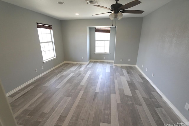 unfurnished room featuring visible vents, baseboards, a ceiling fan, and wood finished floors