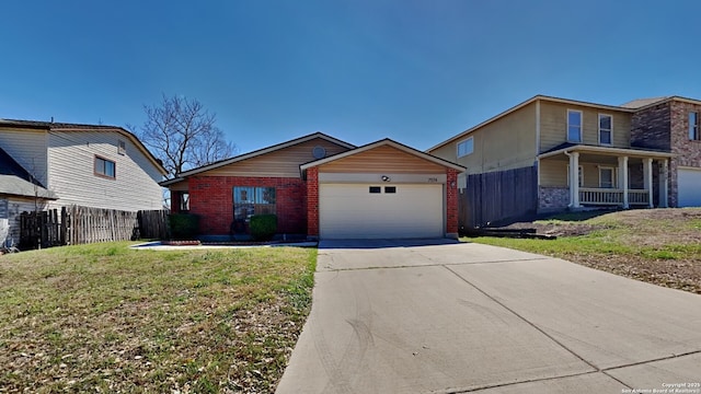 view of front of property with driveway, fence, a front yard, an attached garage, and brick siding